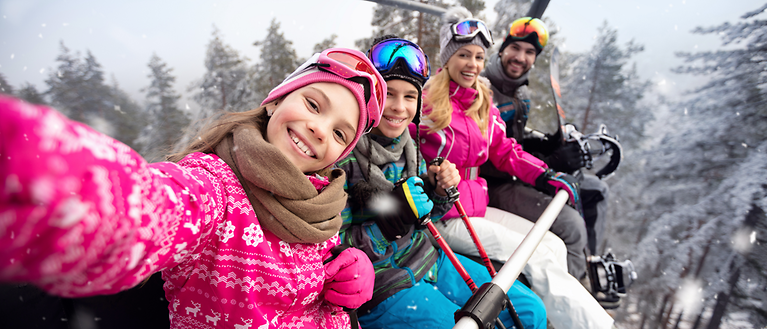 Eine Familie sitzt in einem Skilift und machen ein Selfie. 