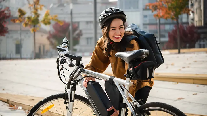Pendlerin auf dem Weg zur Arbeit mit ihrem Pedelec, abgesichert durch die E-Bike-Versicherung der HanseMerkur.